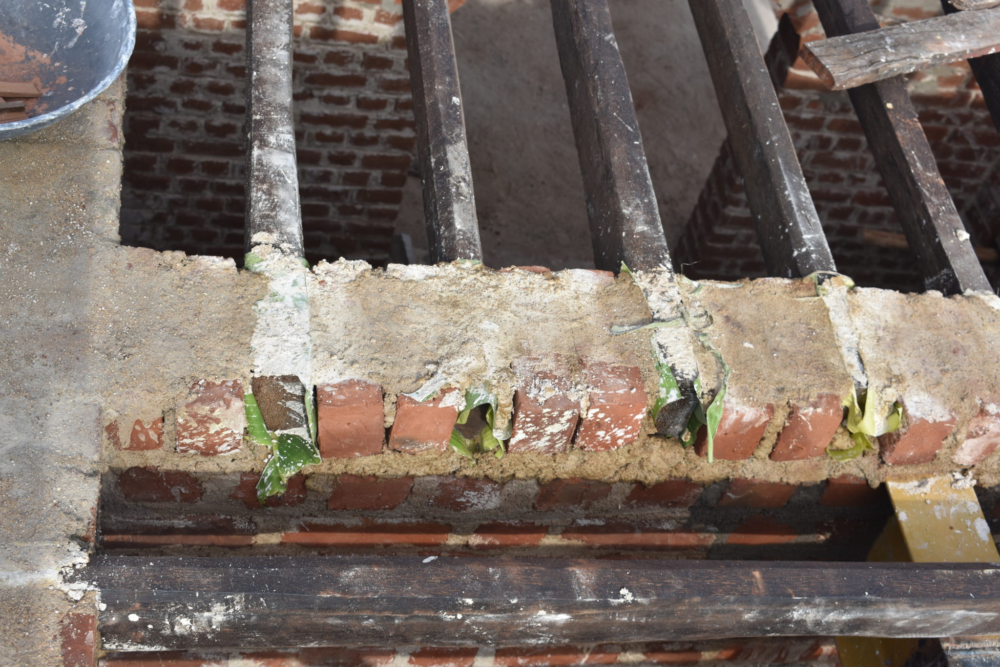 Plantain leaves being used between wood and the bricks to prevent termite attack.